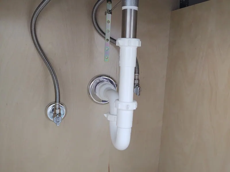 A clean-cut vanity water-line opening under a finished sink cabinet — the kind of detail Excel sweats