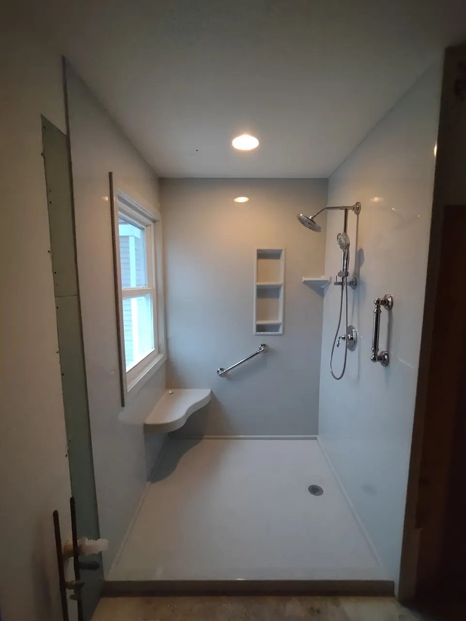 Accessible curbless walk-in shower with a fold-down bench, grab bars, and a handheld sprayer, Chicagoland