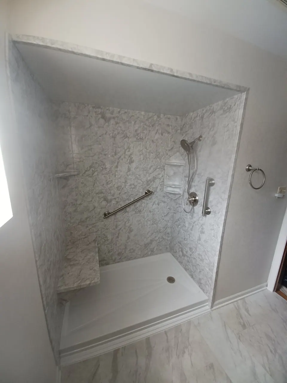 Marble-look walk-in shower with a built-in seat and grab bars, an Excel install