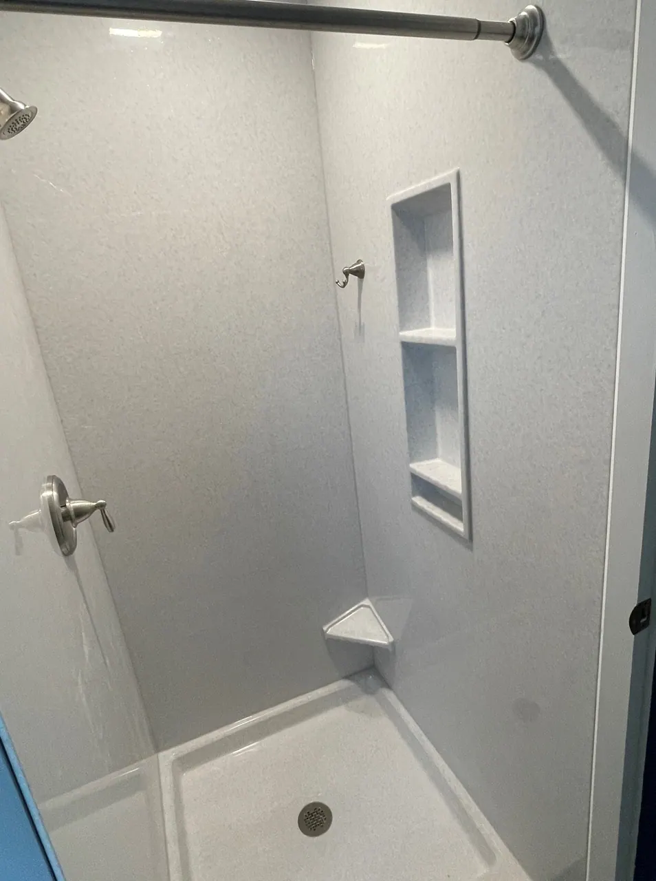 Solid-surface walk-in shower with a built-in corner niche, seat, and brushed-nickel fixtures, Chicagoland